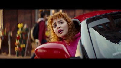 a woman in a pink shirt leaning out of a red car