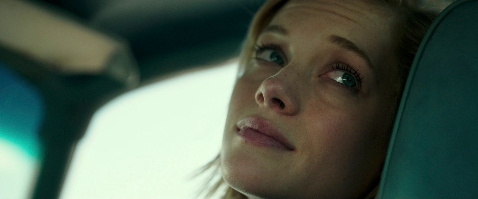 a woman sitting in a car looking out the window