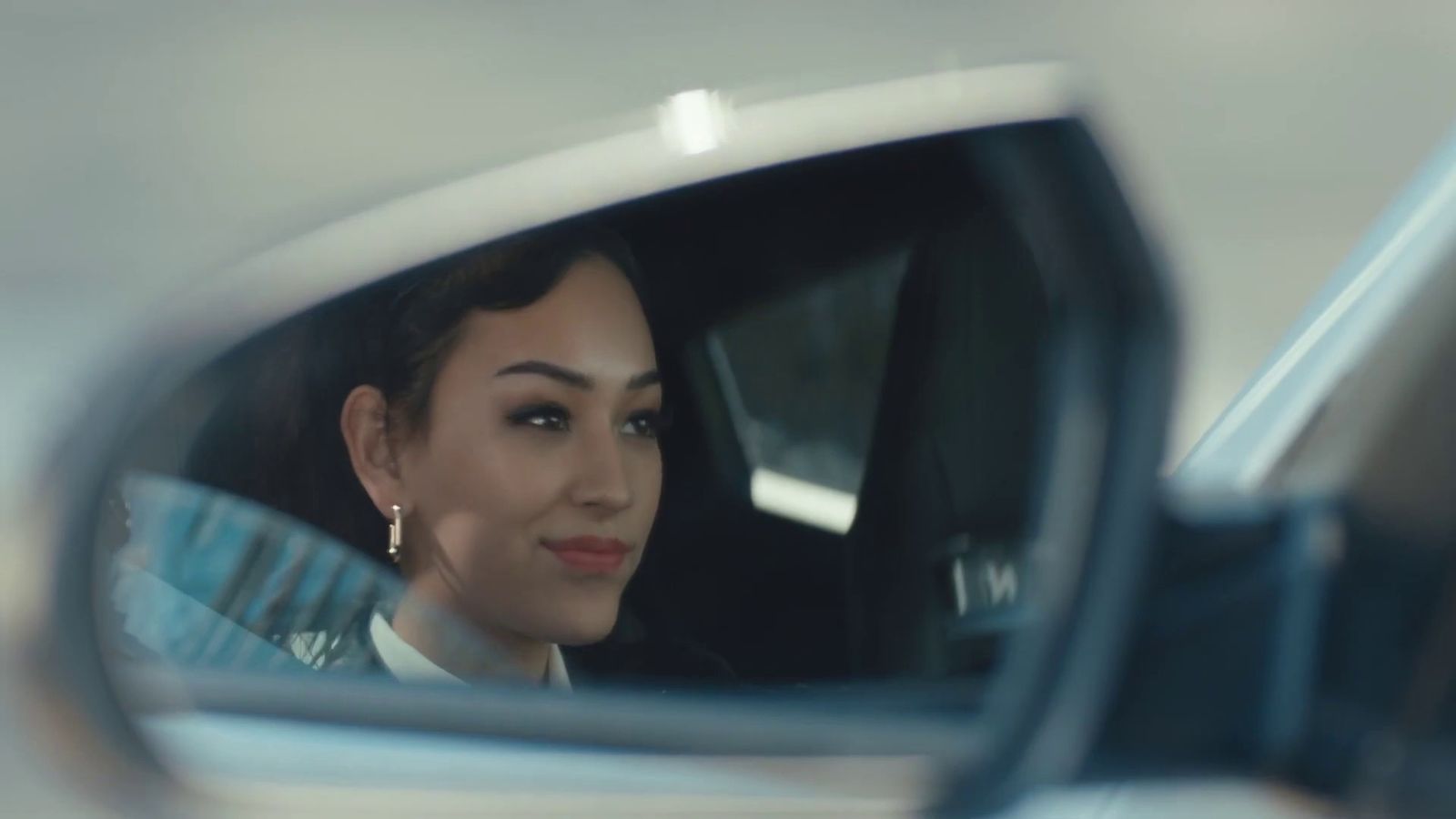 a woman is seen in the side mirror of a car