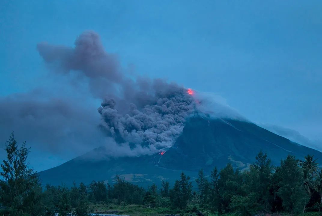 a large plume of smoke rising from a volcano