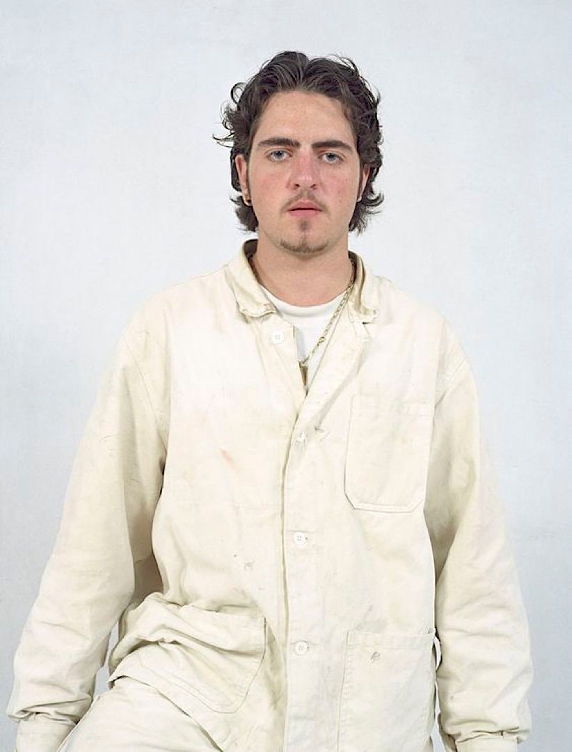 a man in a white shirt sitting on a stool