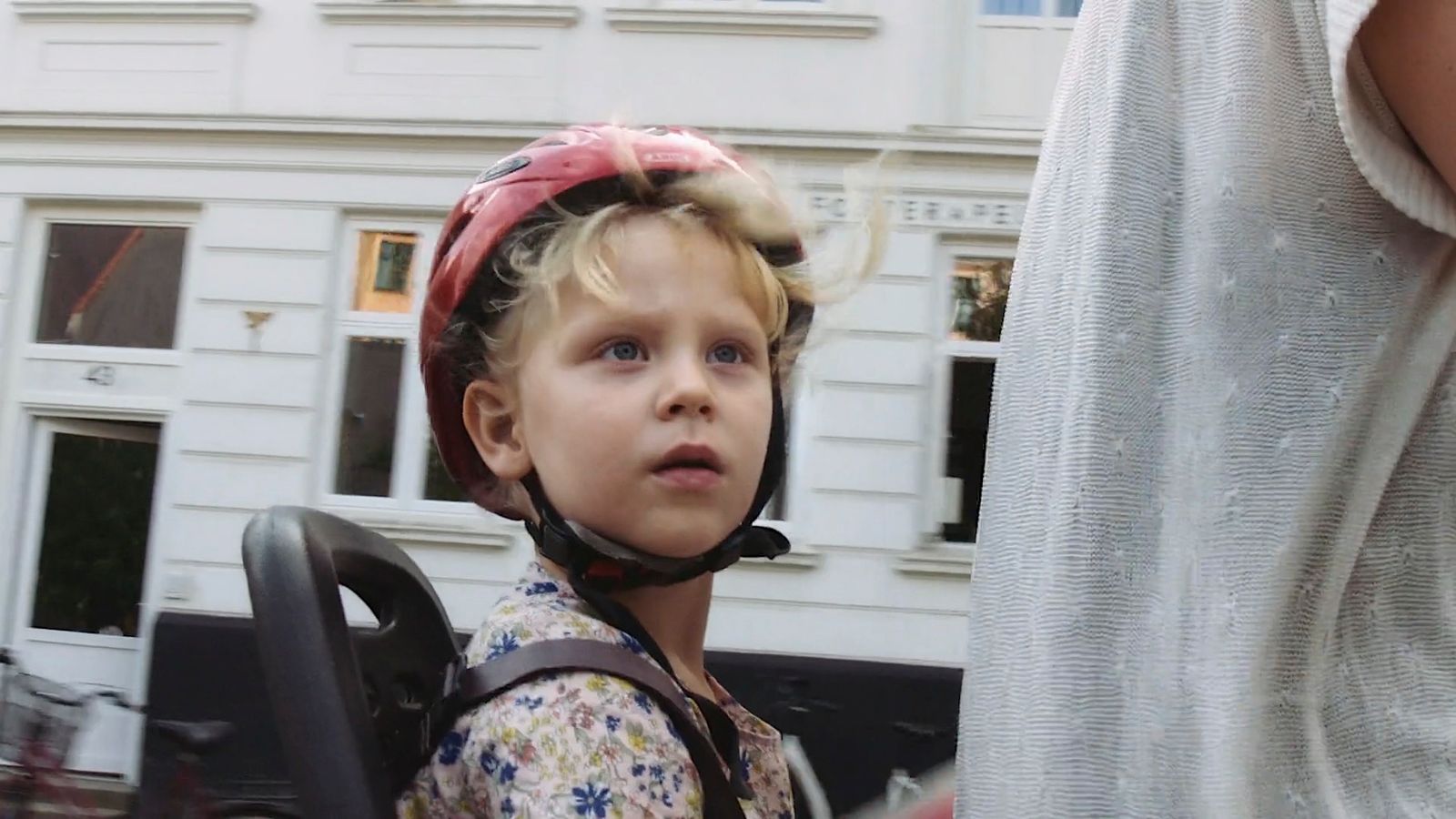 a little girl wearing a helmet and a backpack