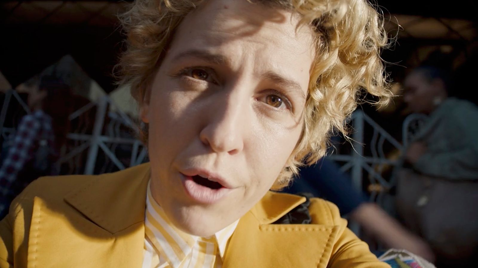 a man with curly hair wearing a yellow jacket