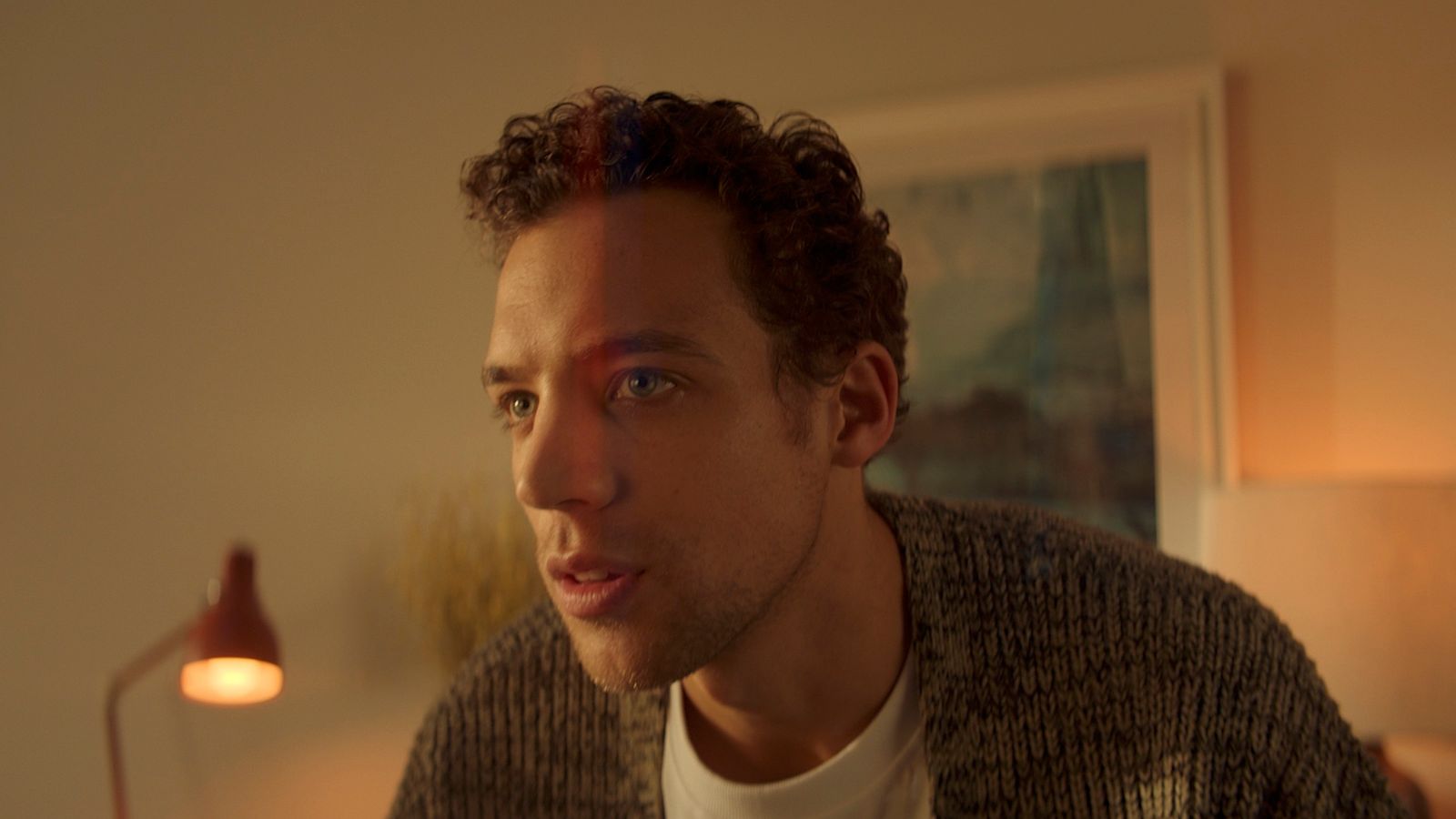 a man with curly hair wearing a sweater