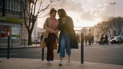 two women standing next to each other on a sidewalk