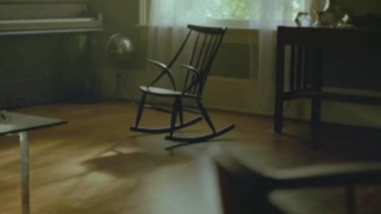 a rocking chair sitting in a living room next to a piano