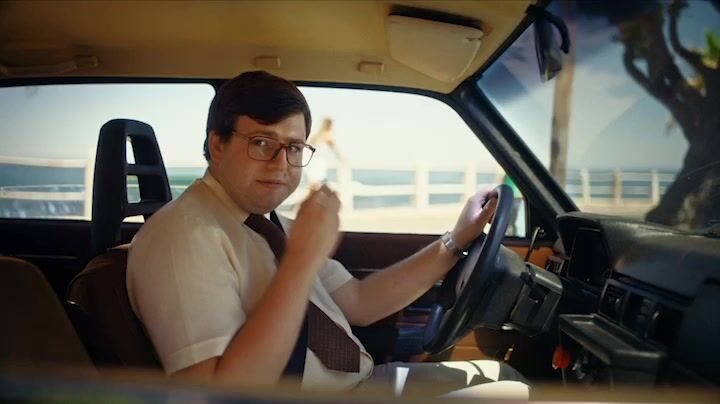 a man sitting in a car with his hands on the steering wheel