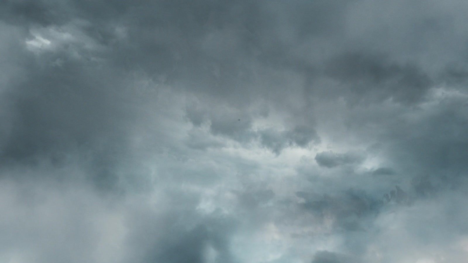 a plane flying through a cloudy sky on a cloudy day