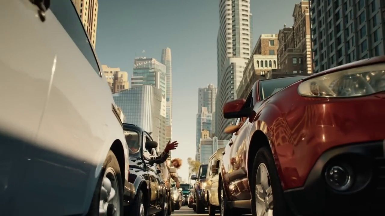 a group of cars driving down a street next to tall buildings