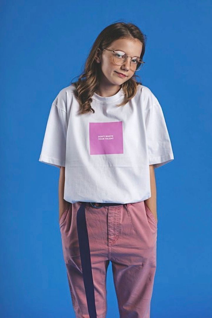 a young girl wearing a white shirt and pink pants