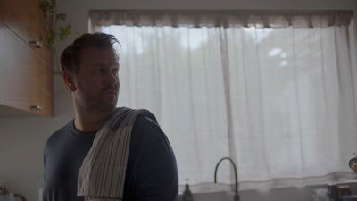 a man standing in a kitchen next to a window