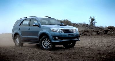 a blue suv driving down a dirt road