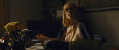 a woman sitting at a desk with a pen in her hand