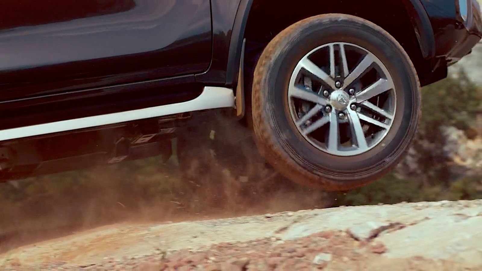 a black truck driving down a dirt road