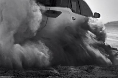 a black and white photo of a car on a beach