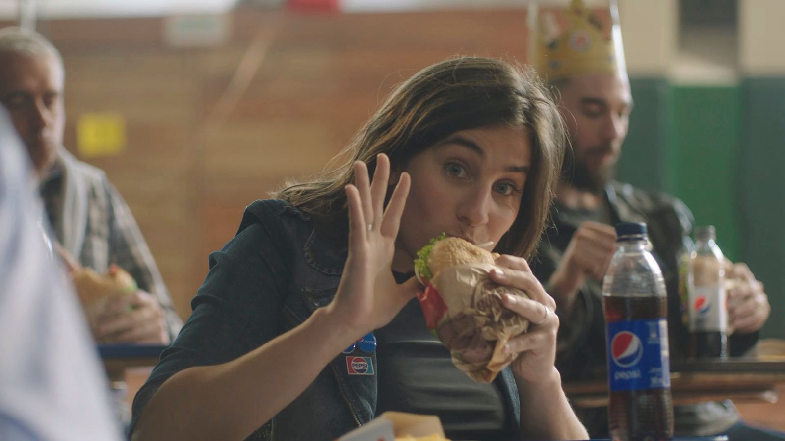 a woman sitting at a table eating a sandwich