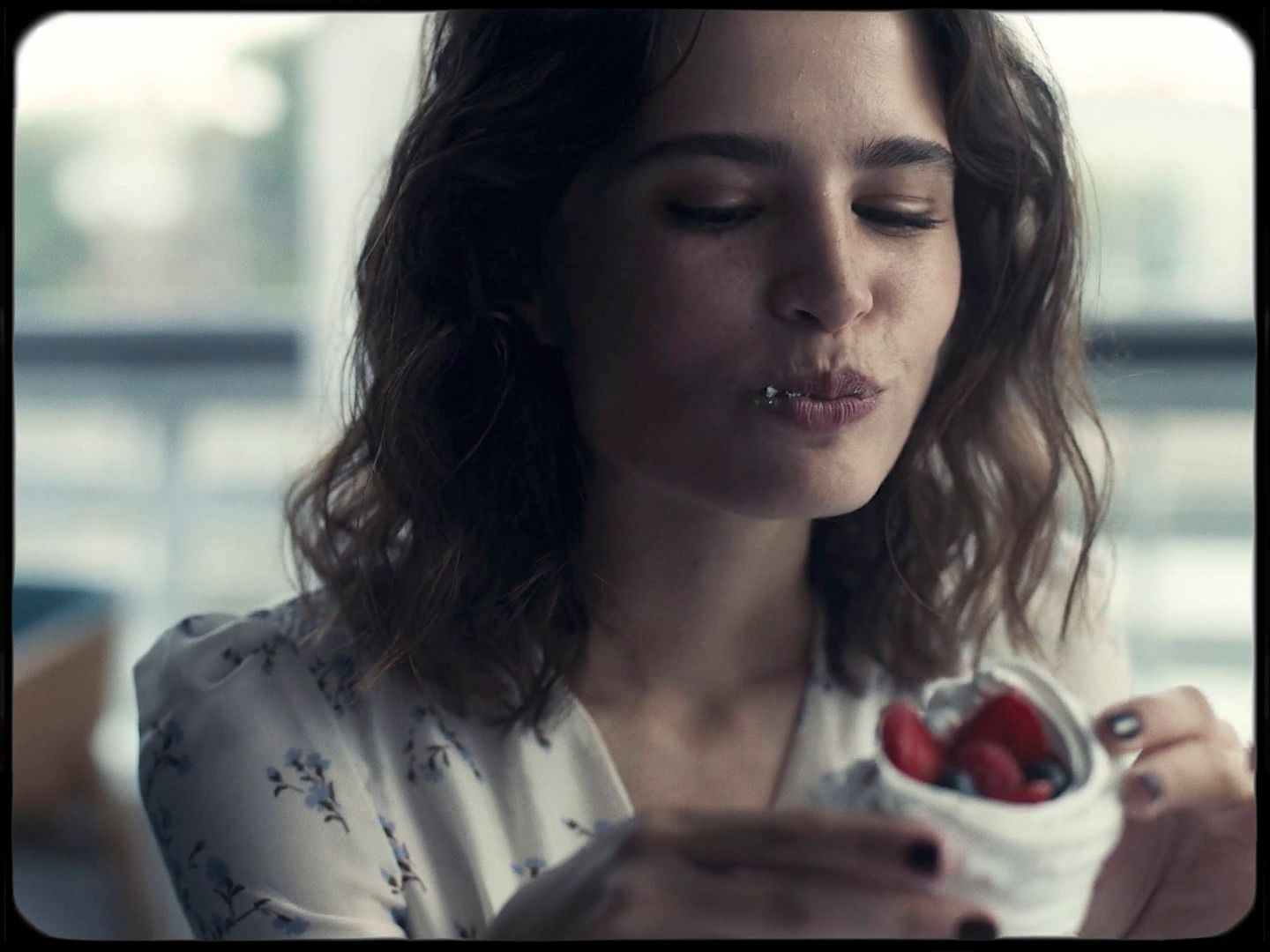 a woman holding a container of strawberries in her hand