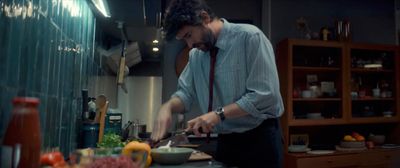 a man in a kitchen chopping vegetables on a cutting board