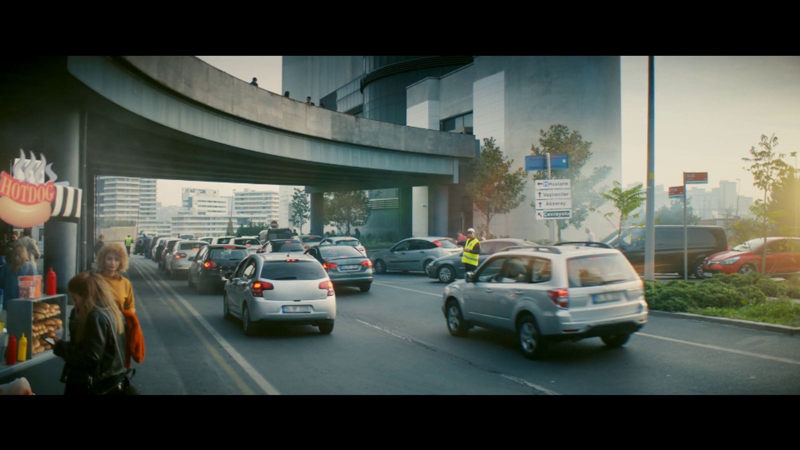 a group of cars driving down a street next to tall buildings