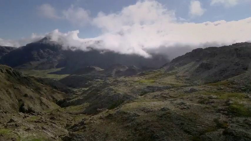 a view of a mountain range with clouds in the distance