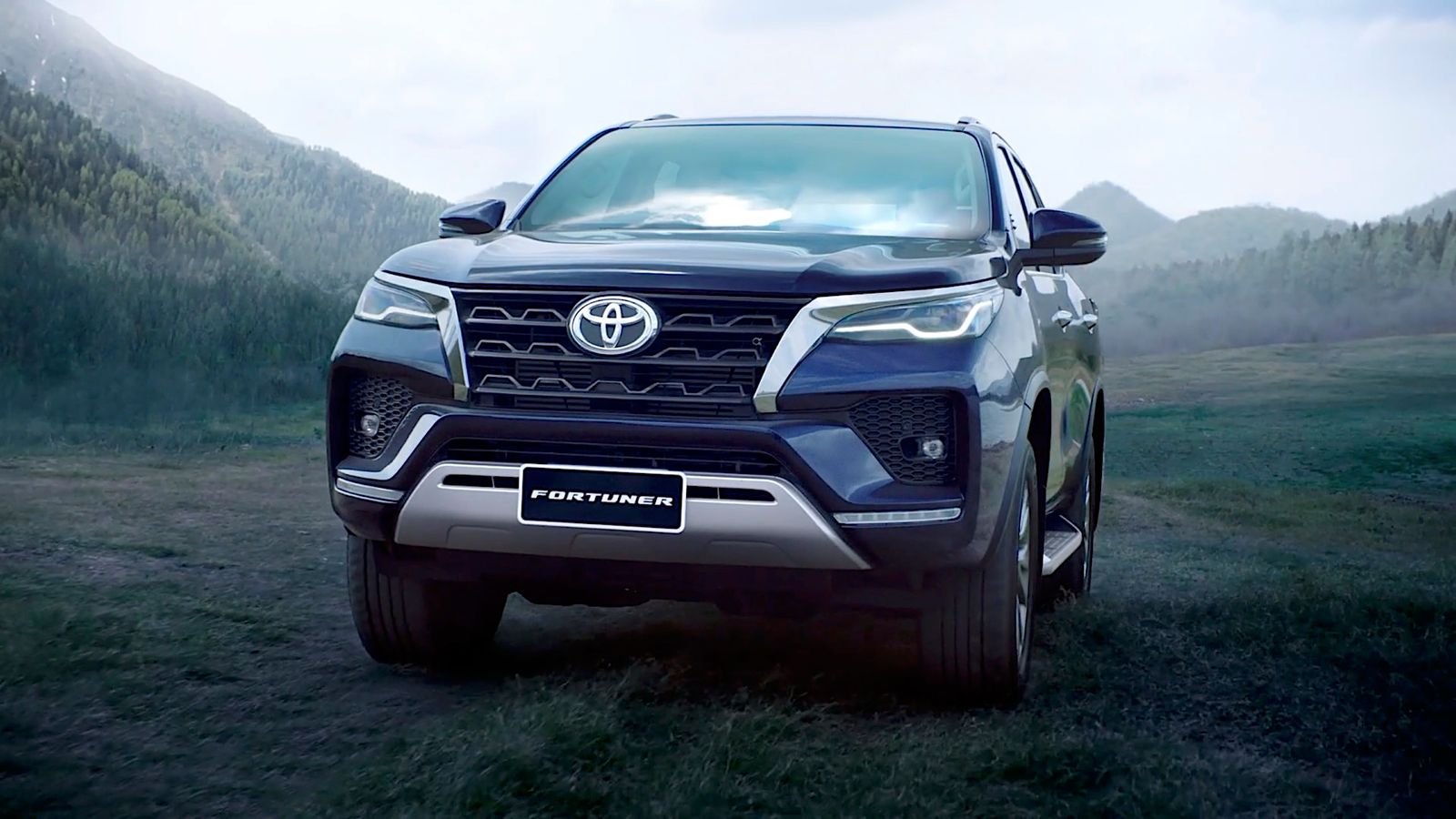 the front end of a black suv parked in a field