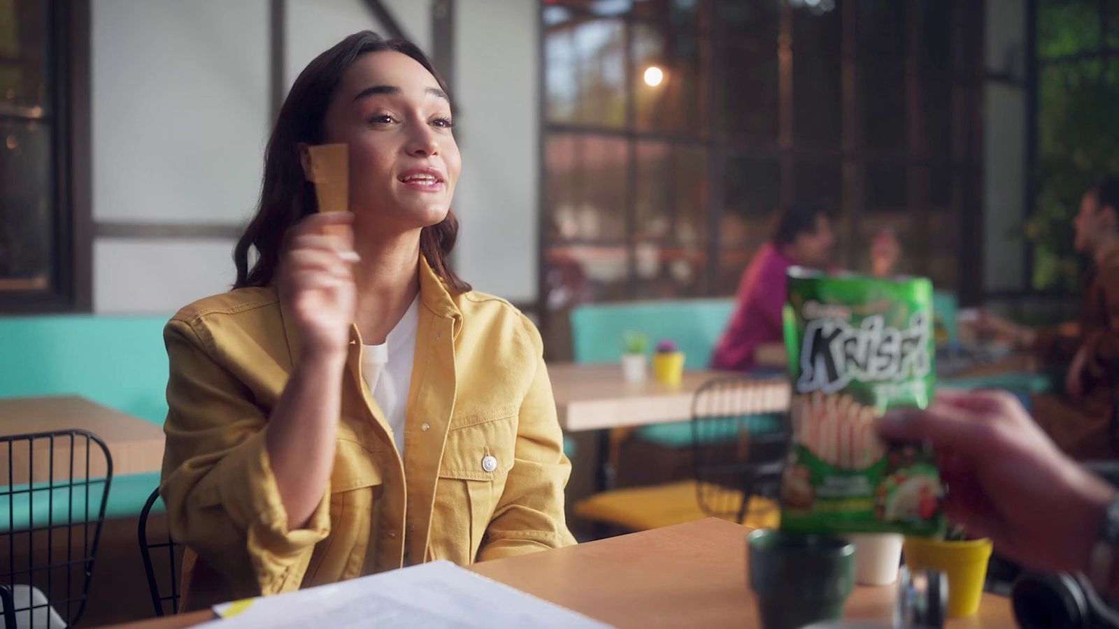 a woman sitting at a table with a box of krispy kreme