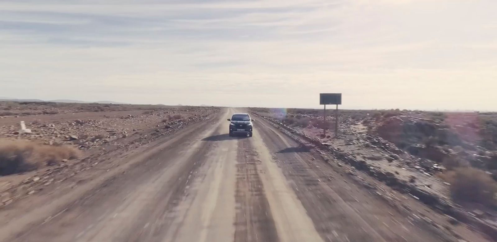 a car driving down a dirt road in the desert