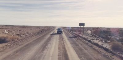 a car driving down a dirt road in the desert