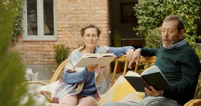 a man and woman sitting on a bench reading books