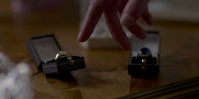 a person touching a ring in a box on a table