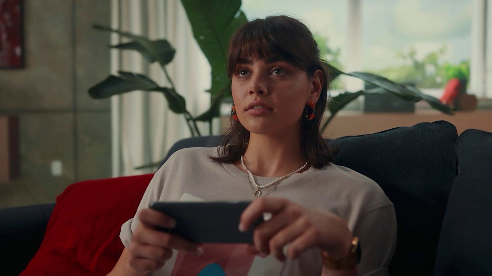 a woman sitting on a couch holding a remote control