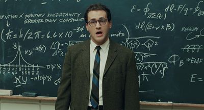 a man standing in front of a blackboard with lots of writing on it