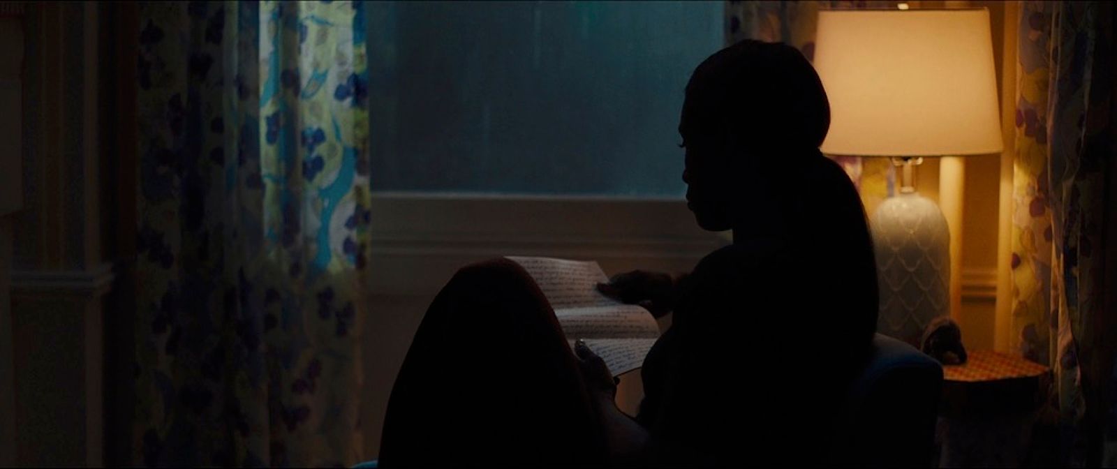 a person sitting in a dark room reading a book