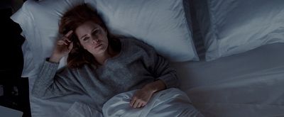 a woman laying in a bed with white sheets