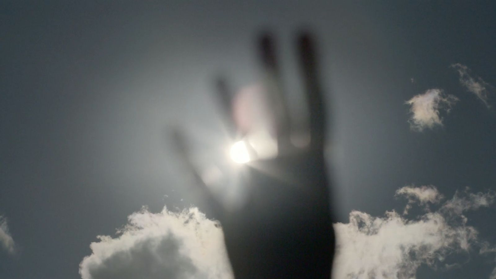 a blurry image of a hand reaching up into the sky