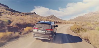 a silver car driving down a desert road