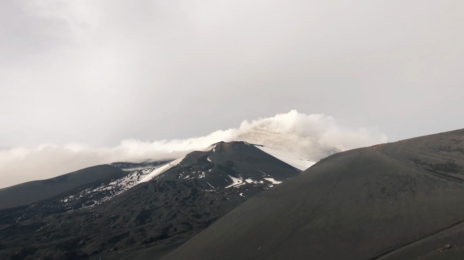 a mountain covered in snow under a cloudy sky