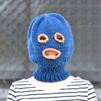 a person wearing a blue knitted mask with holes in it