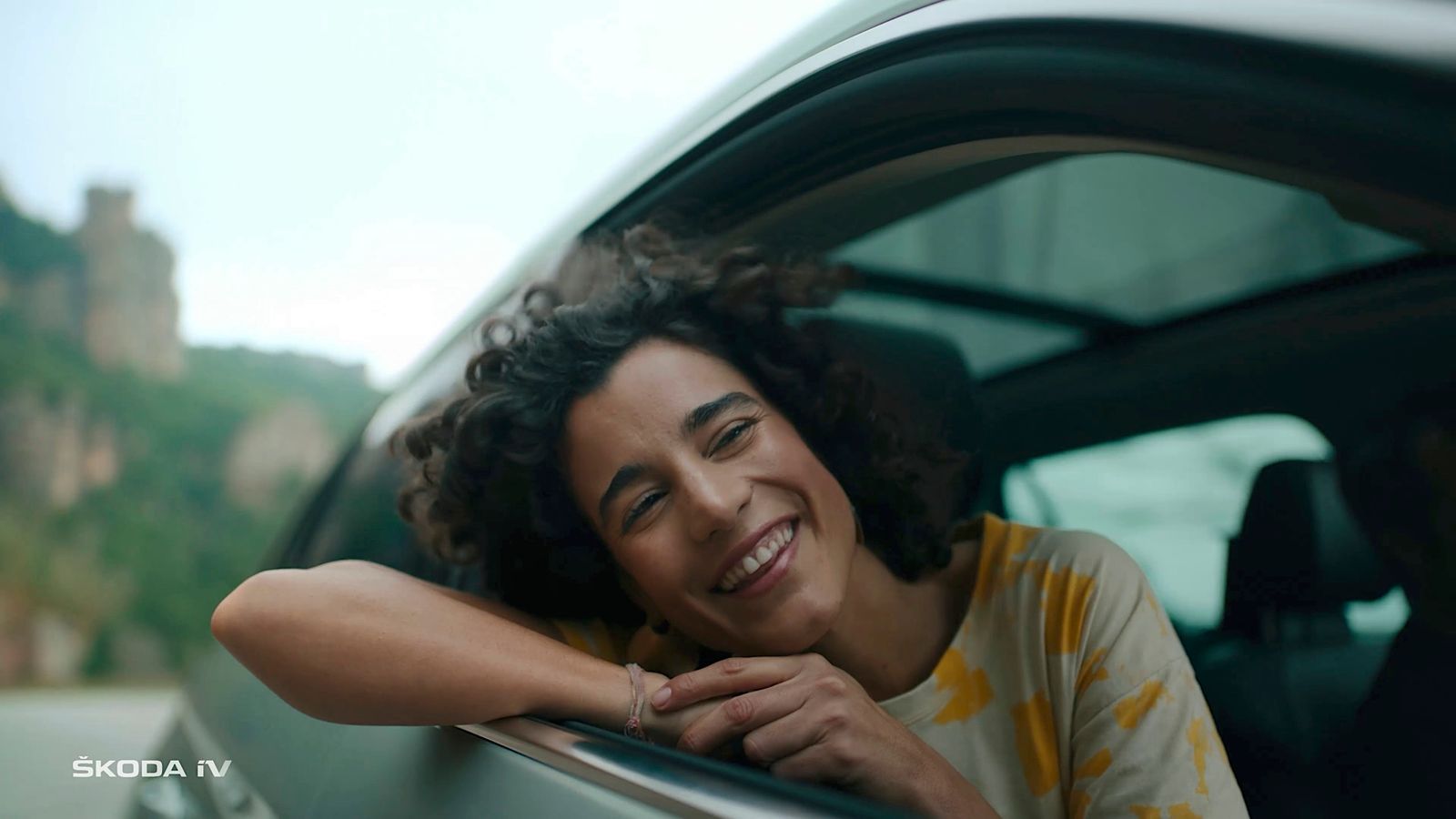 a smiling woman leaning out of a car window