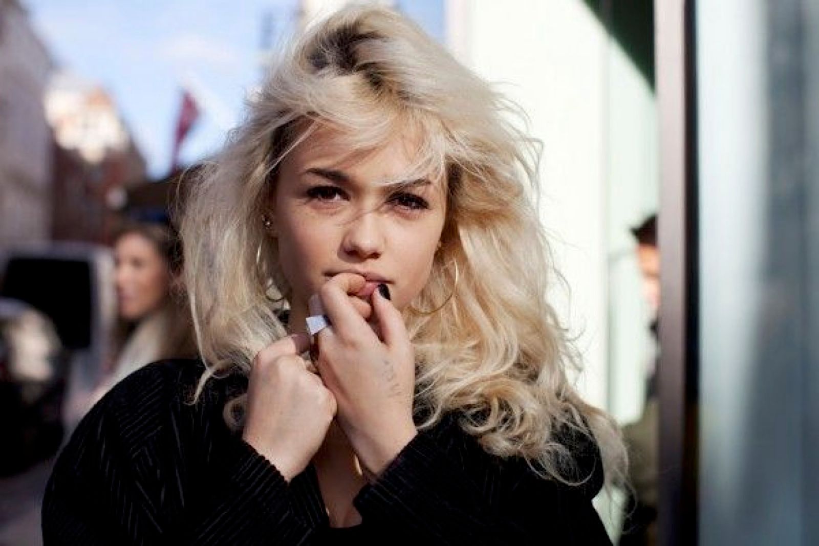 a woman smoking a cigarette on a city street