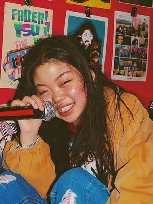 a woman sitting on a bed holding a microphone