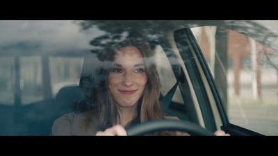 a woman sitting in a car with a steering wheel