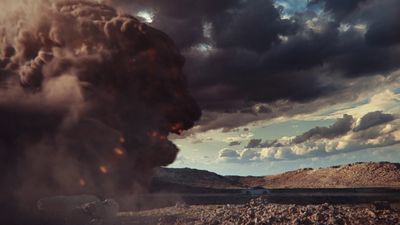 a large plume of smoke rising from the ground