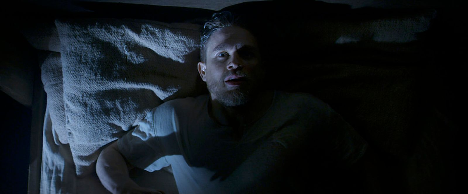 a man laying in bed in the dark