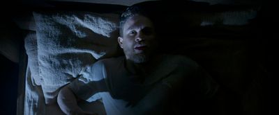 a man laying in bed in the dark