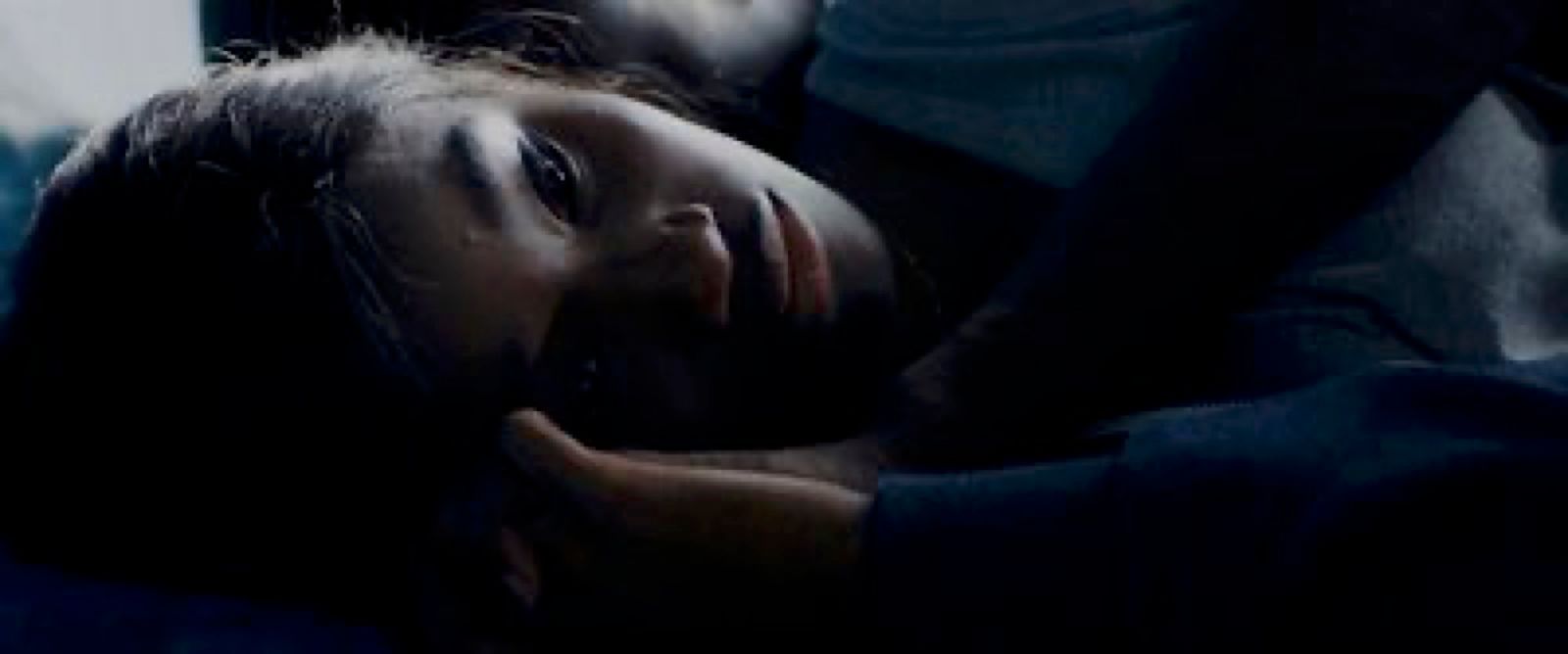 a woman laying on a bed in the dark