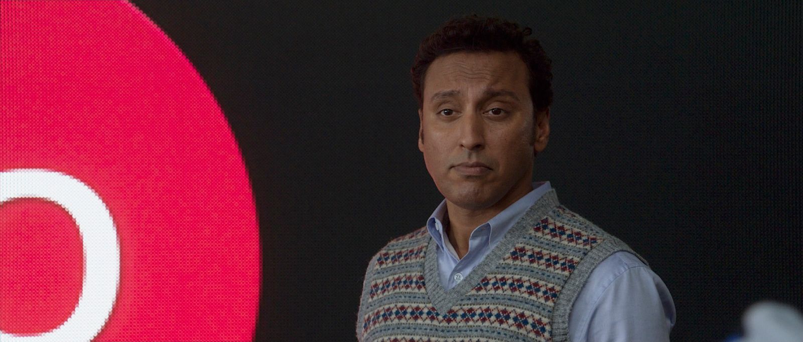 a man in a sweater vest standing in front of a target sign