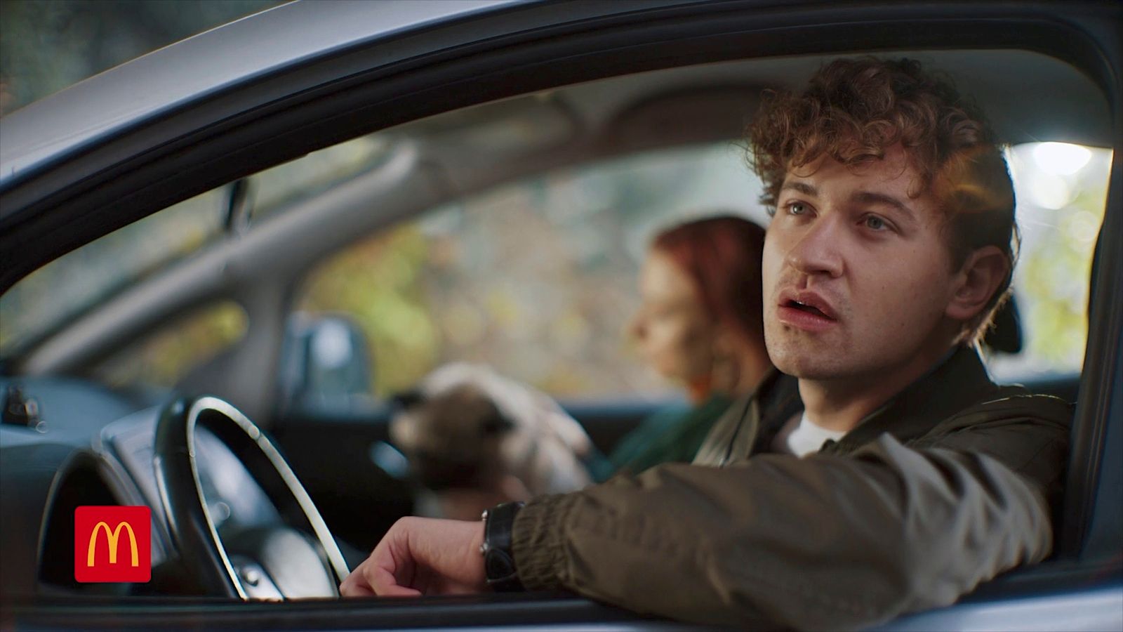 a man driving a car with a woman behind him