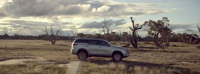 a silver truck driving through a dry grass field