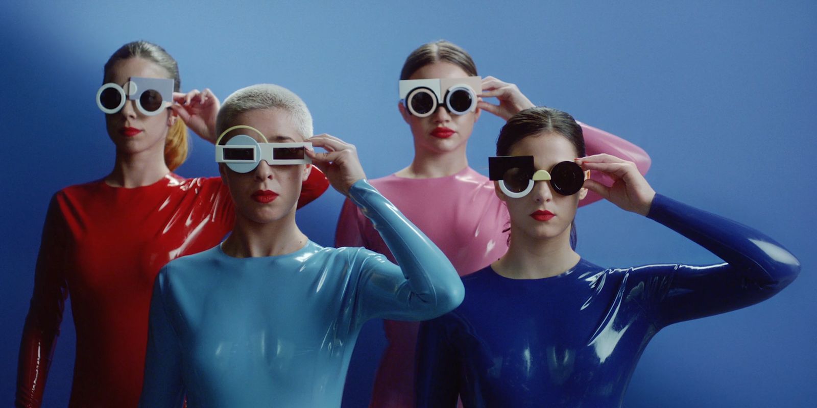 a group of women in bodysuits and sunglasses